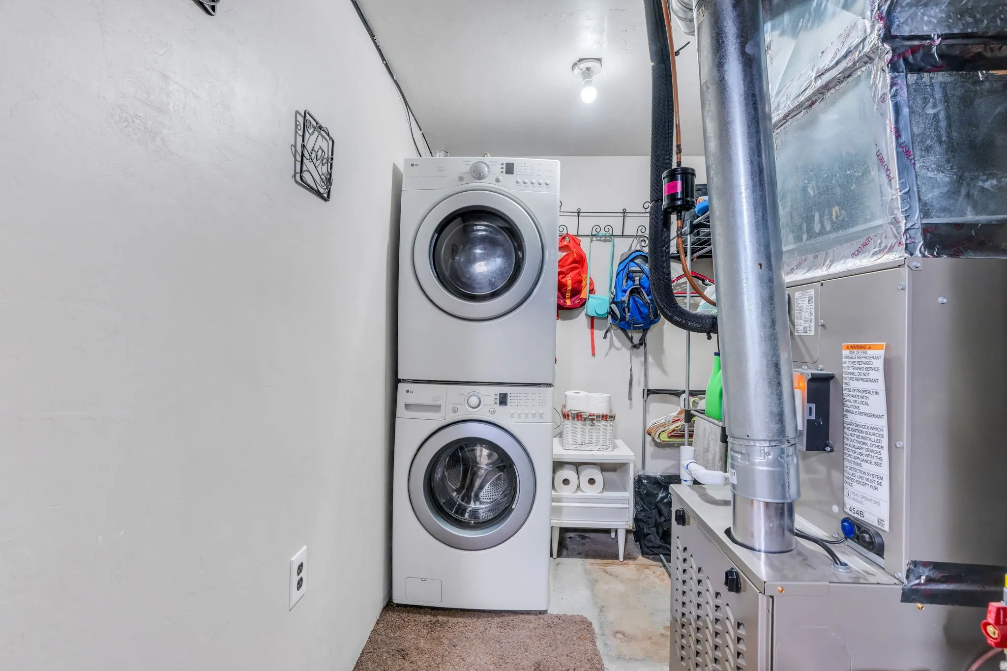Laundry area featuring a stacked washer and dryer, adjacent to an HVAC unit