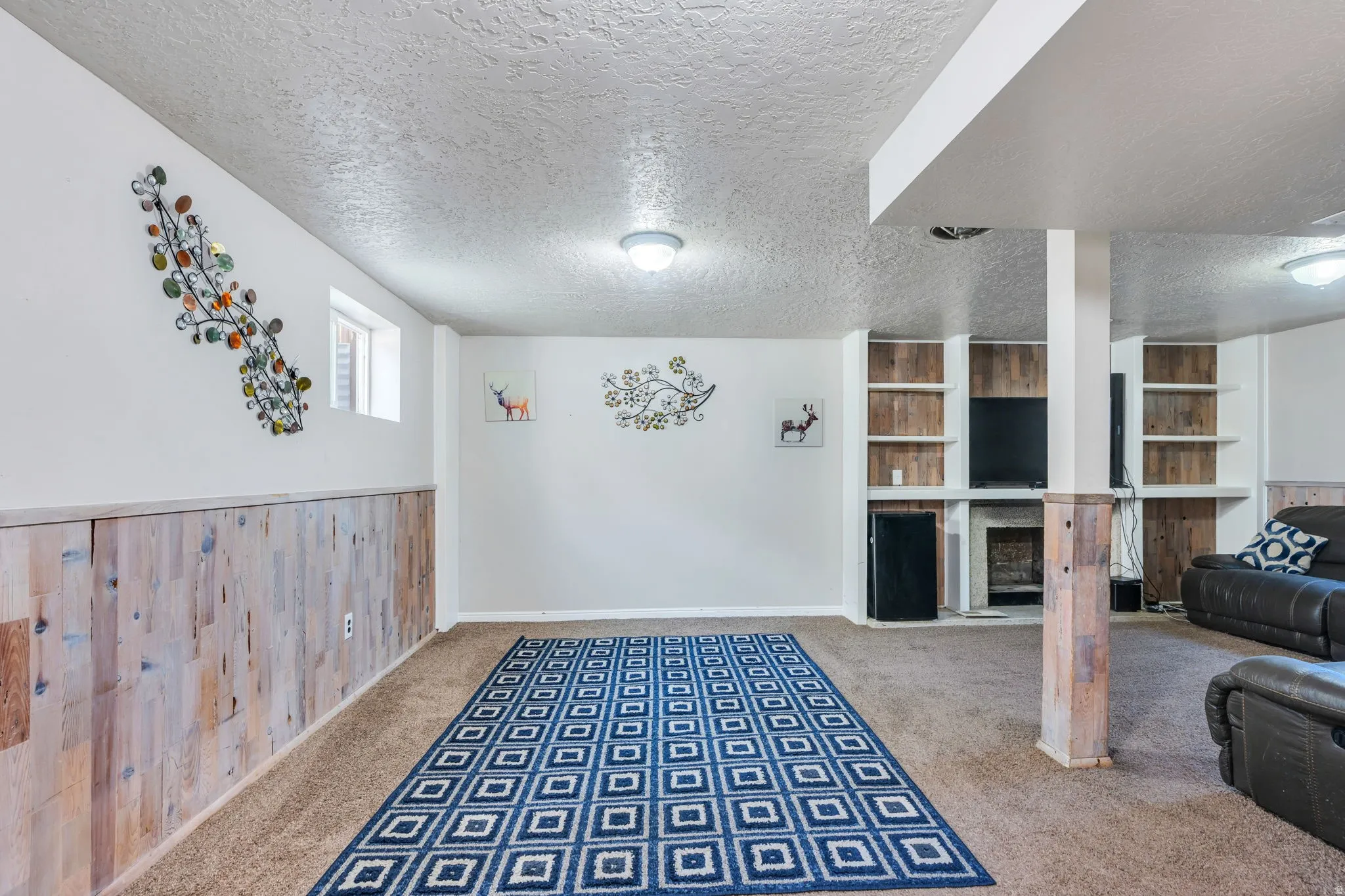 Carpeted entertainment area featuring built-in shelving, a recessed media alcove, and a fireplace with a stone surround