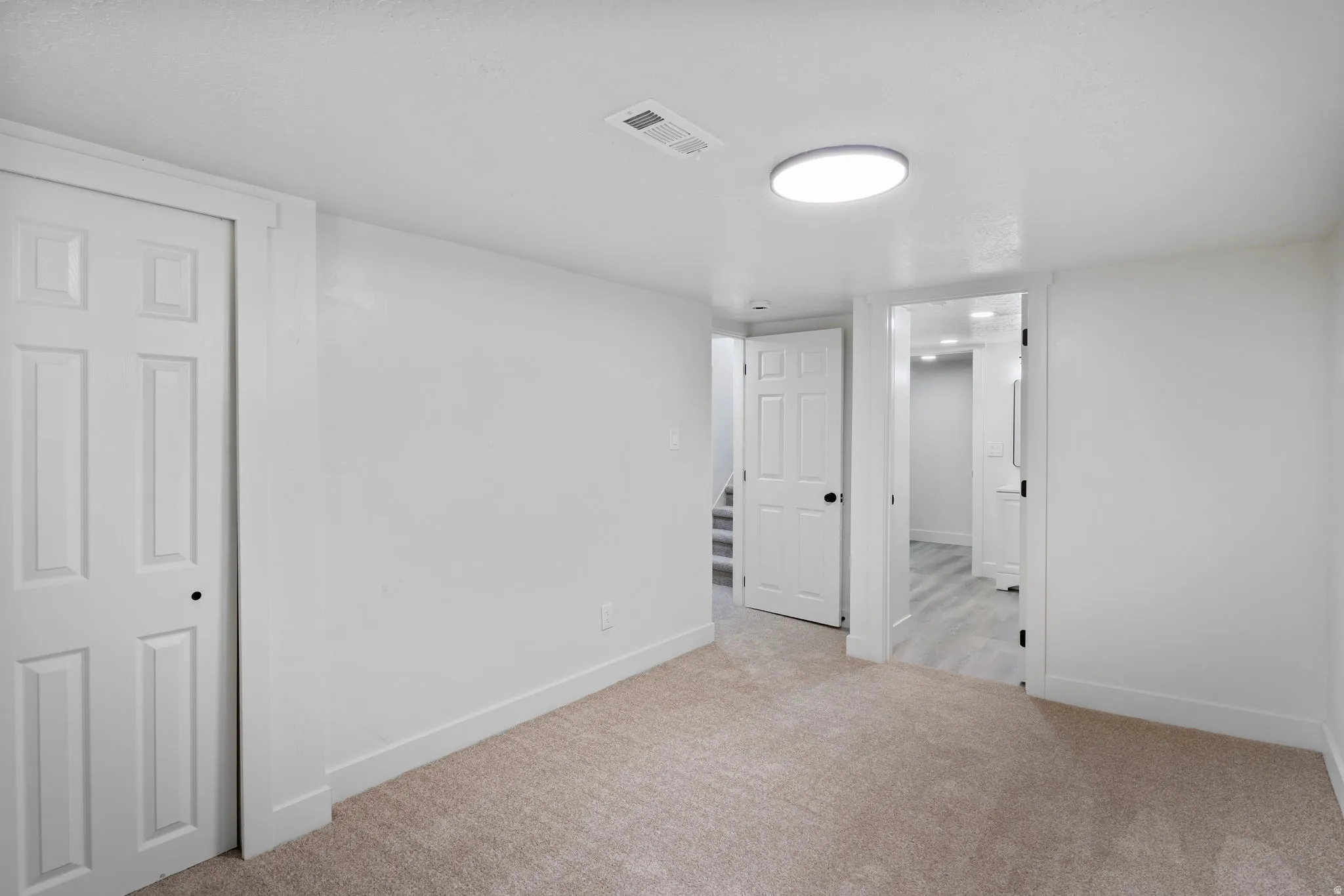 Carpeted room featuring white walls, white trim, and a flush-mount circular ceiling light