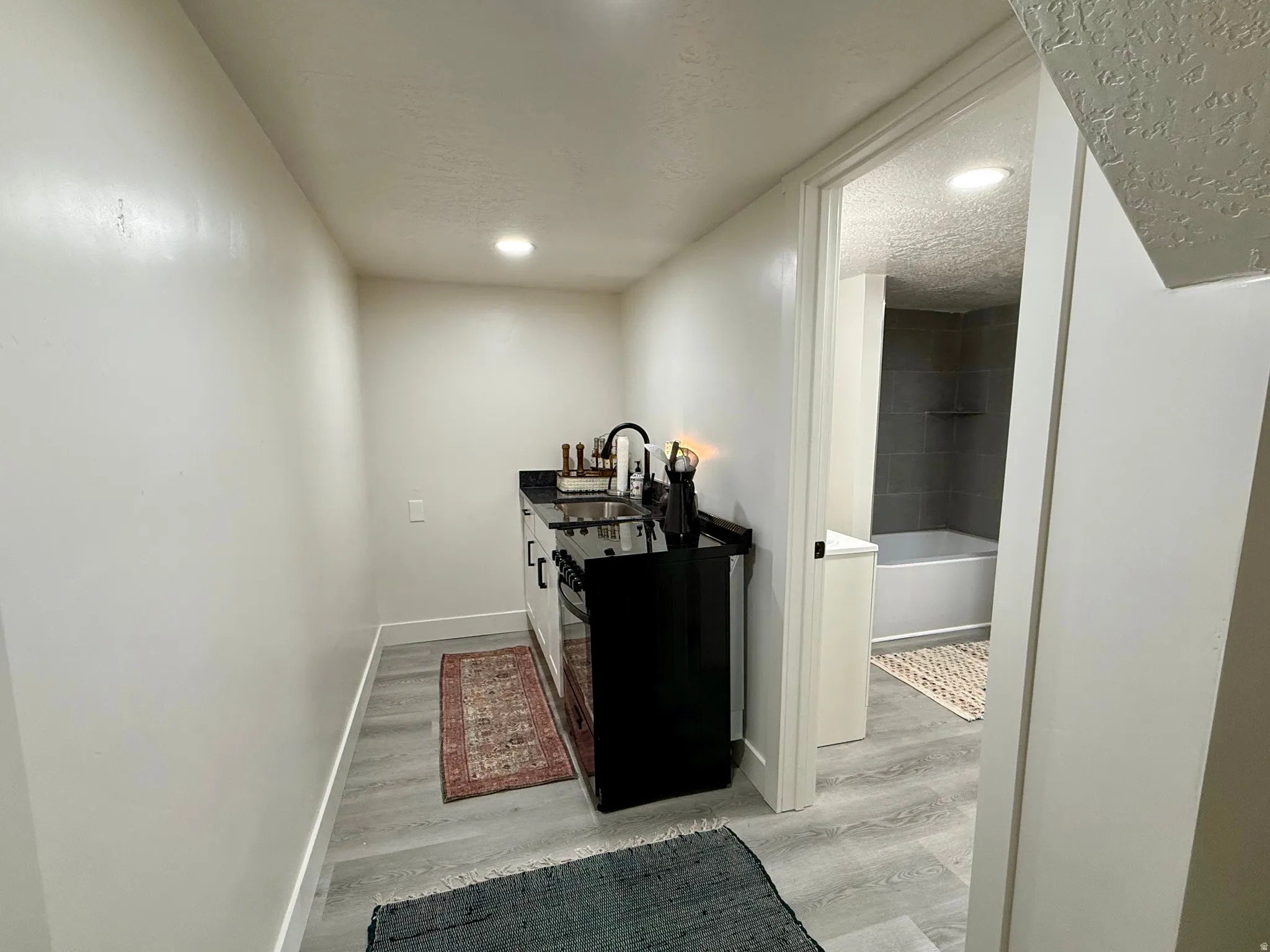 Compact kitchenette featuring a dark countertop, sink with a matte black faucet, and integrated dark cabinetry