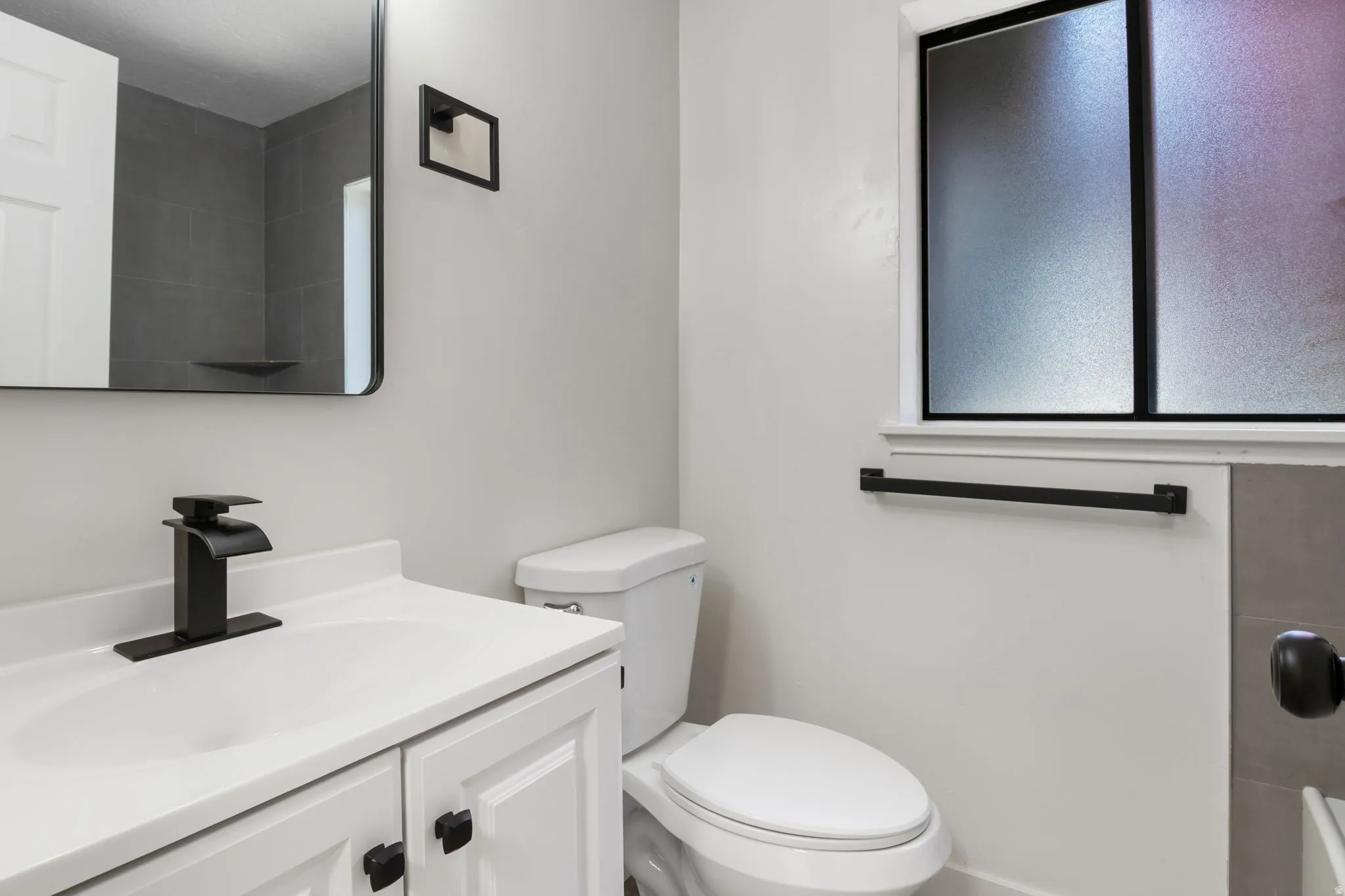 Bathroom featuring a white vanity with panel cabinetry and matte black hardware