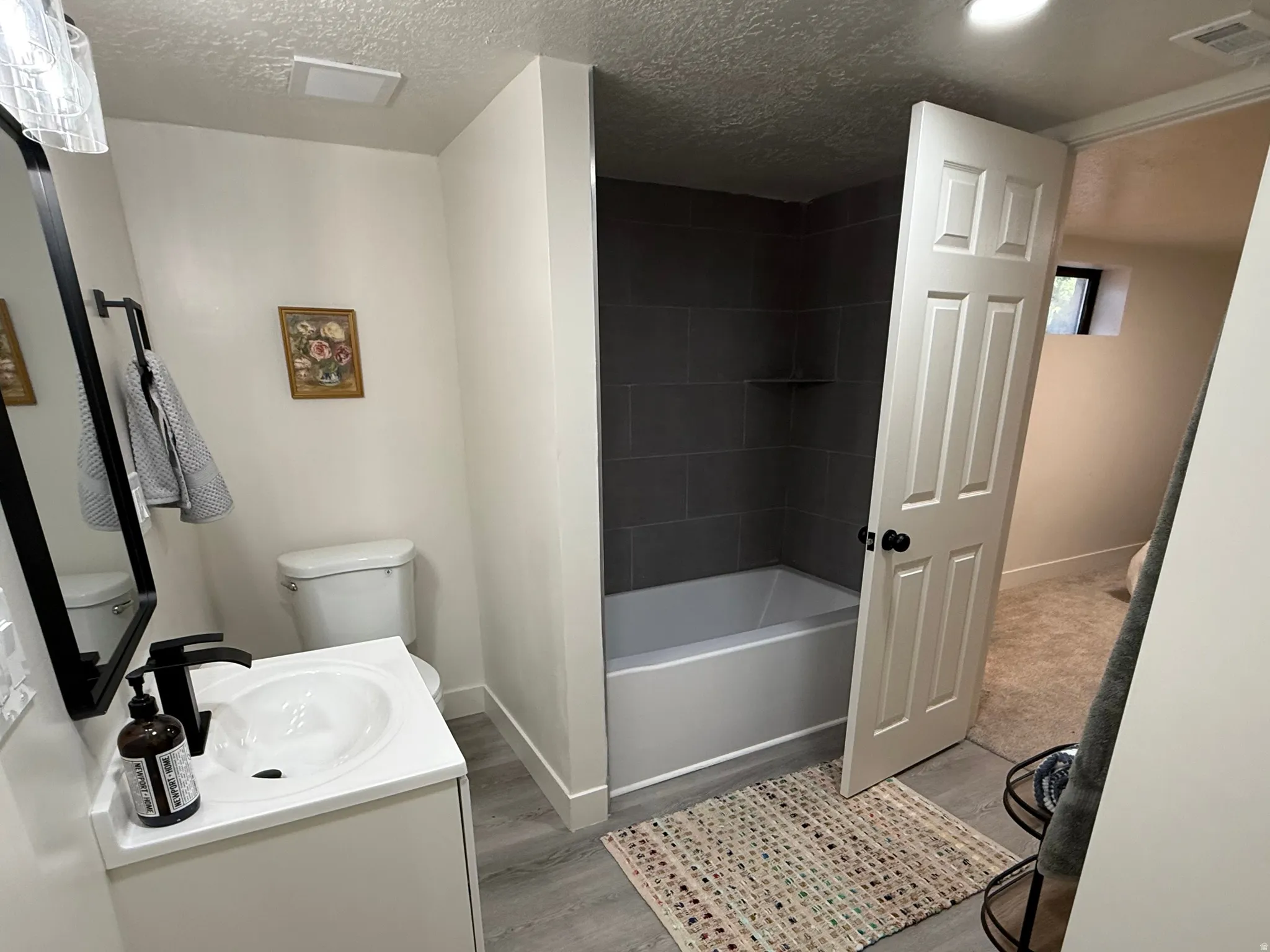 Bathroom featuring a white vanity with an integrated sink, matte black faucet, and a large wall-mounted mirror