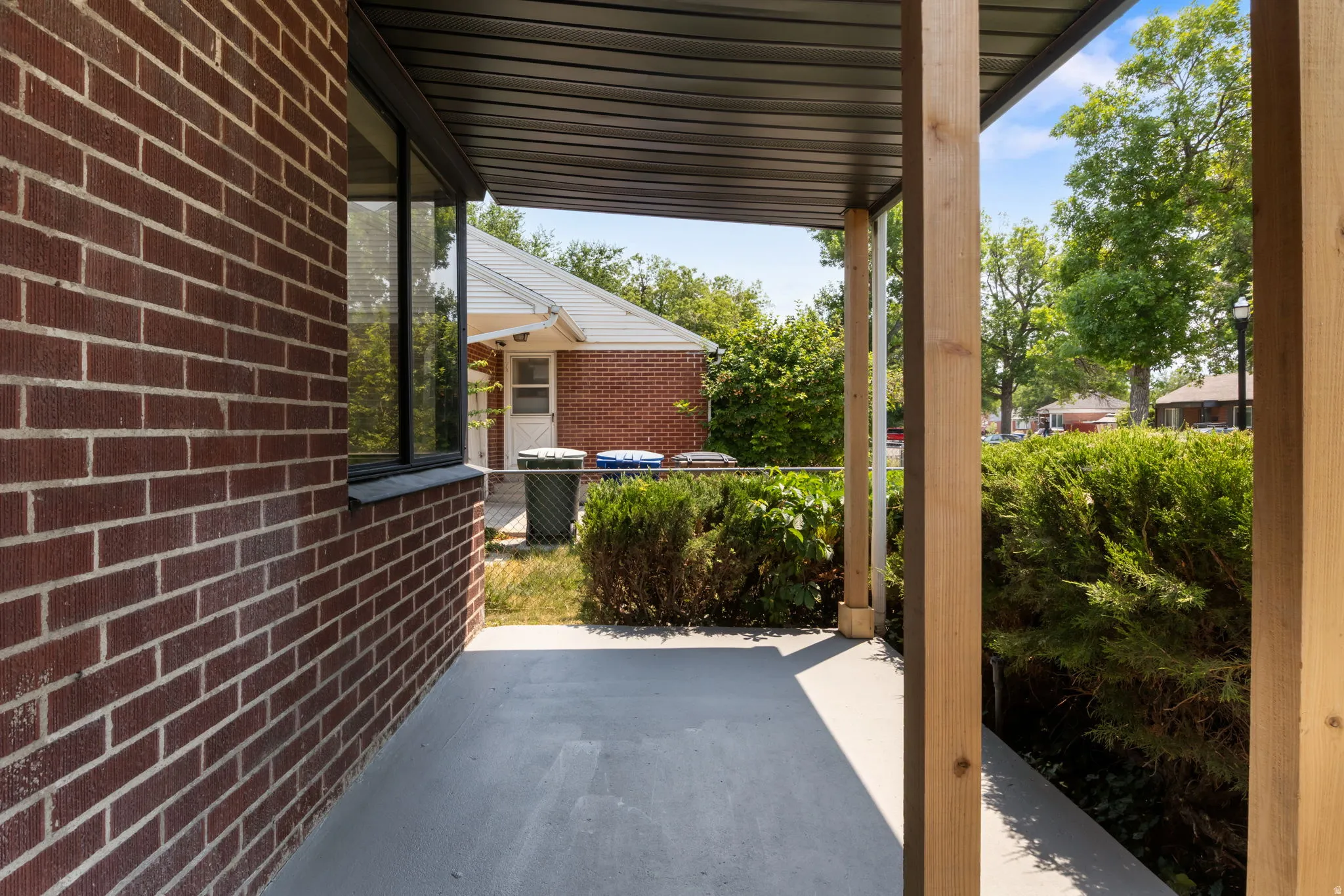 Front Entrance - Covered porch with wood support beams, brick exterior, and a solid surface floor