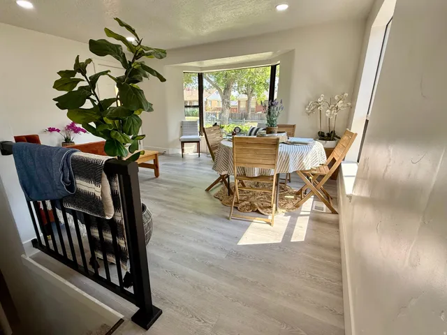 Bright living area featuring light wood-finish flooring, a bay window, recessed lighting, and a black spindle railing