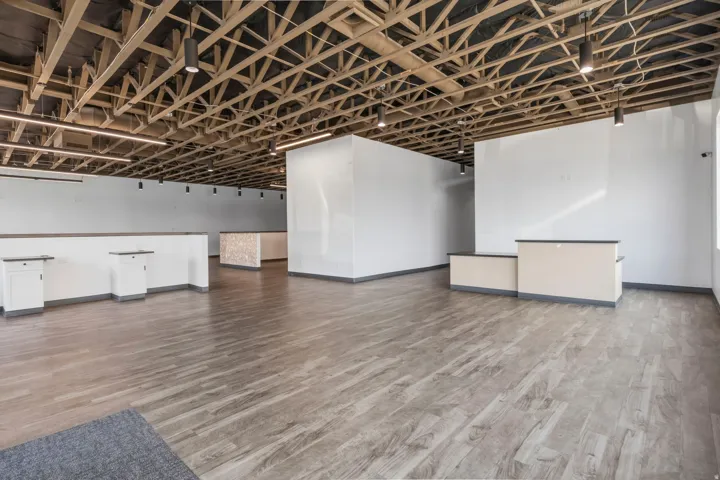 Spacious interior featuring exposed wood ceiling trusses, recessed lighting, wood-finish flooring, and white partition walls
