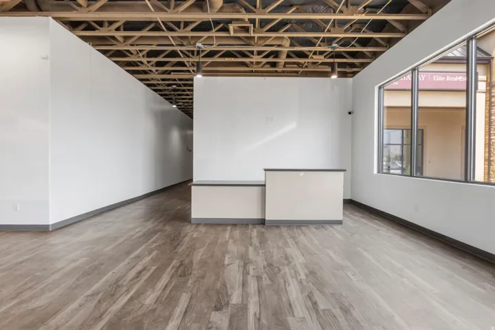 Spacious commercial interior featuring wood-finish flooring and an exposed wood beam ceiling