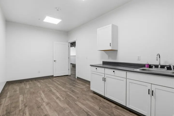 Contemporary room featuring wood-finish flooring, white walls, and a recessed square light fixture