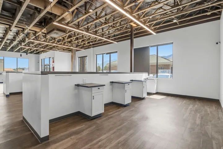 Open-concept space featuring wood-finish flooring and an exposed ceiling with linear lighting