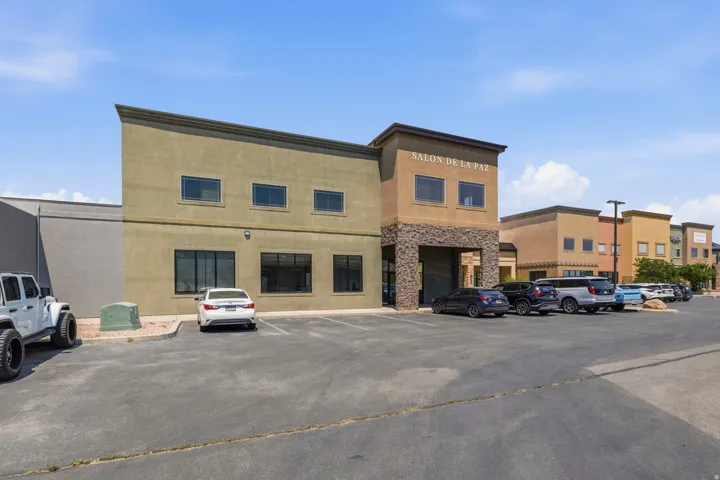 Two-story commercial building featuring a stucco exterior with stone accents and dark-framed windows