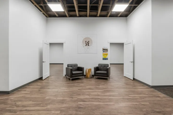 Spacious interior featuring wood-finish flooring, white walls, and an exposed beam ceiling