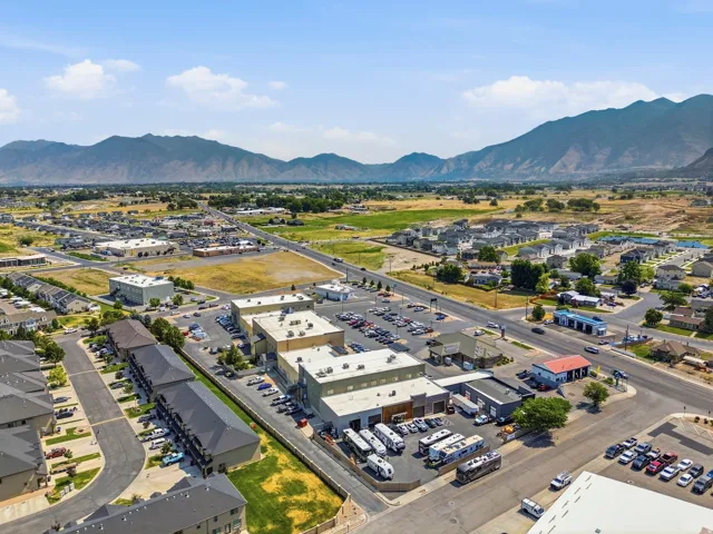 Aerial perspective showcasing commercial properties with expansive paved parking areas and multiple building structures under clear skies