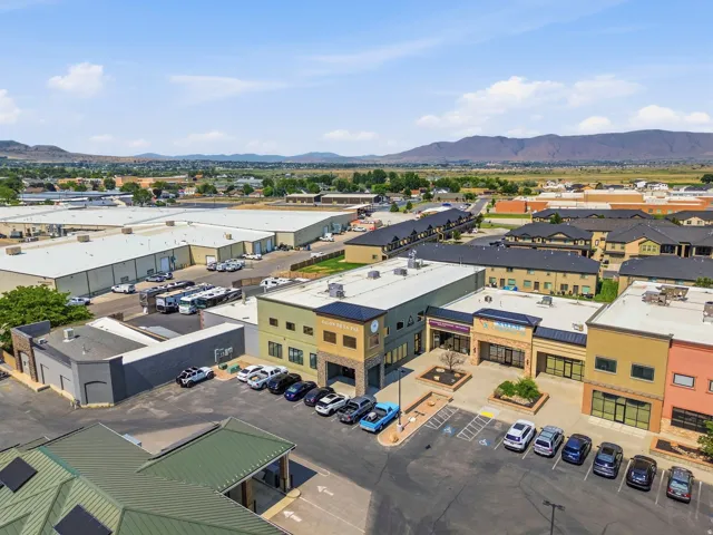 Commercial complex with diverse exterior facades, a paved parking lot, and mountain backdrop