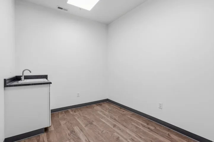 Compact utility area featuring a white base cabinet with a dark countertop and an undermount sink