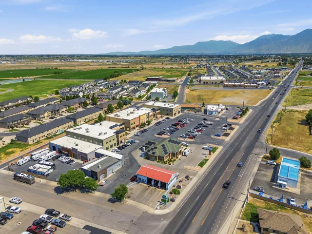 Aerial perspective showcasing commercial properties with expansive parking areas, multiple business facades, and direct road frontage