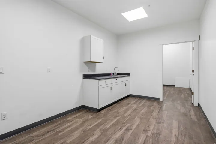 Room featuring wood-finish flooring, white walls, and a corner wet bar