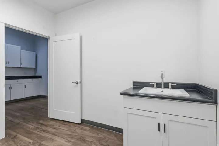 White cabinetry with modern hardware, a countertop basin sink, and a brushed nickel faucet
