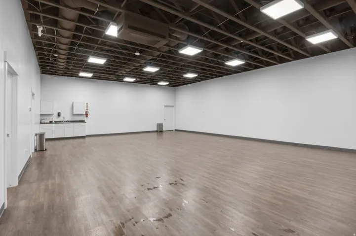 Spacious commercial interior featuring an exposed beam ceiling with recessed lighting