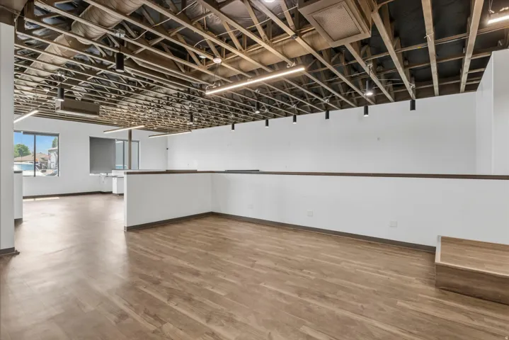Open-concept commercial space featuring high exposed ceilings and wood-finish flooring