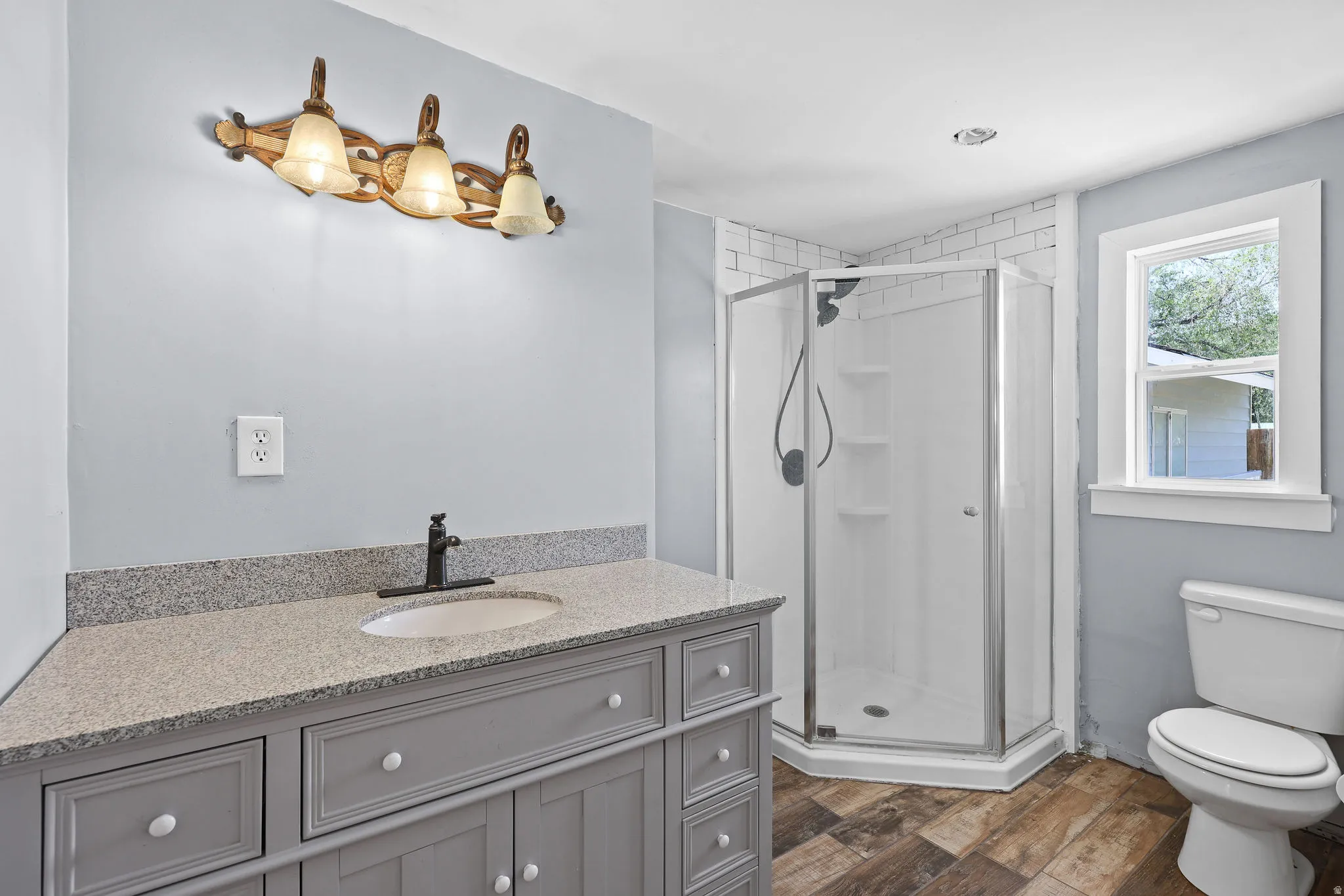 Bathroom featuring a corner vanity with a light granite countertop, undermount sink, and matte black faucet