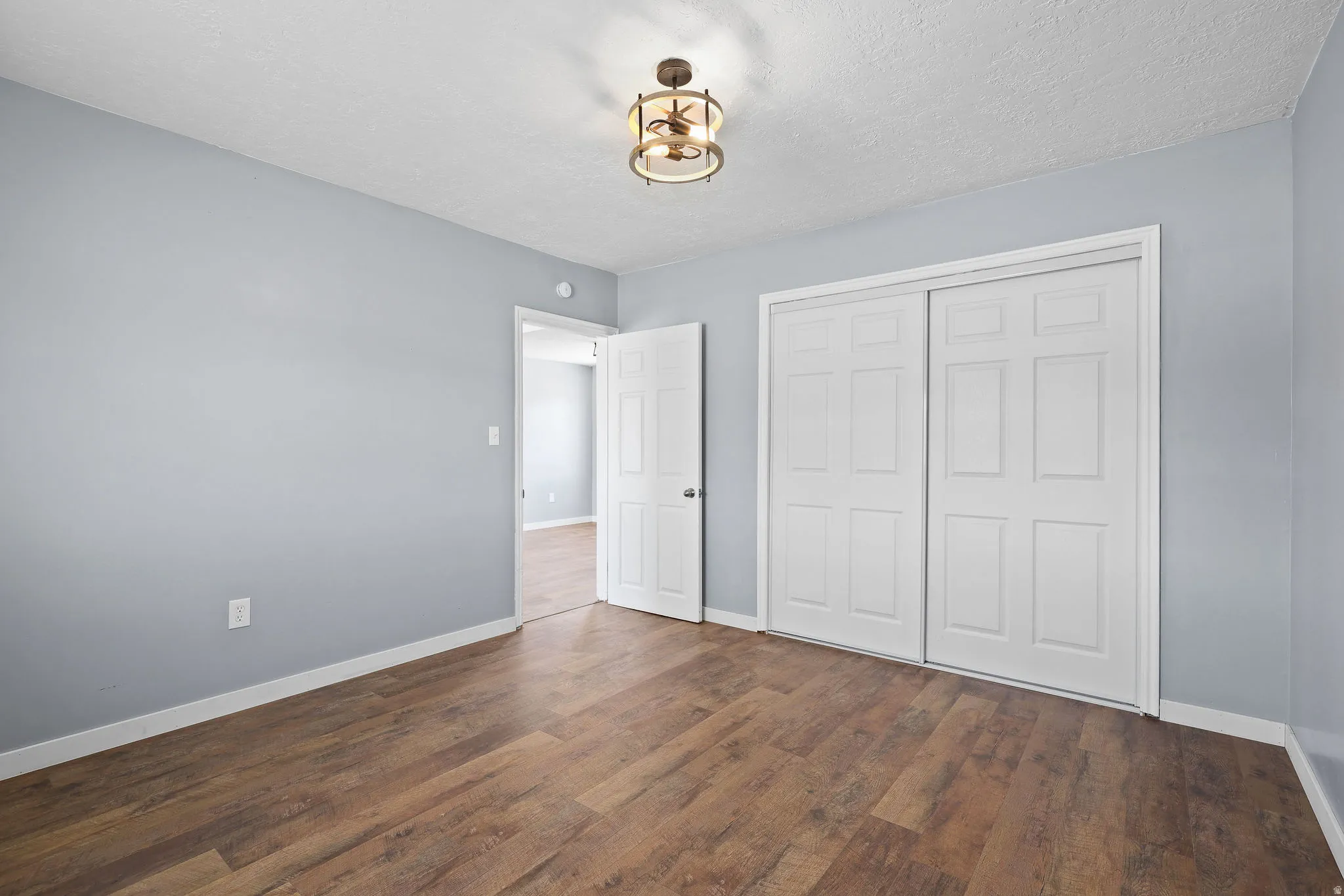 Room featuring wood-finish flooring, light blue walls, white baseboards, and a semi-flush ceiling light fixture