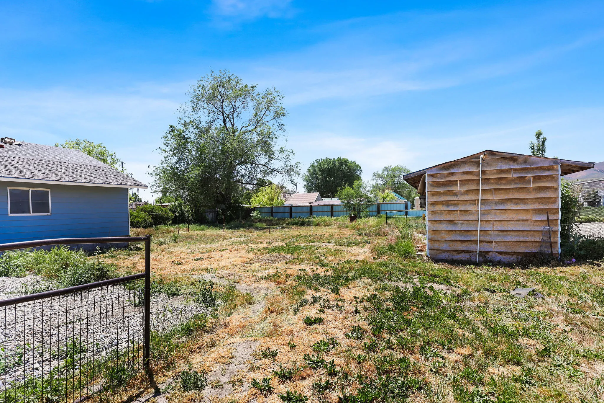 Expansive open lot featuring a perimeter fence and mature trees