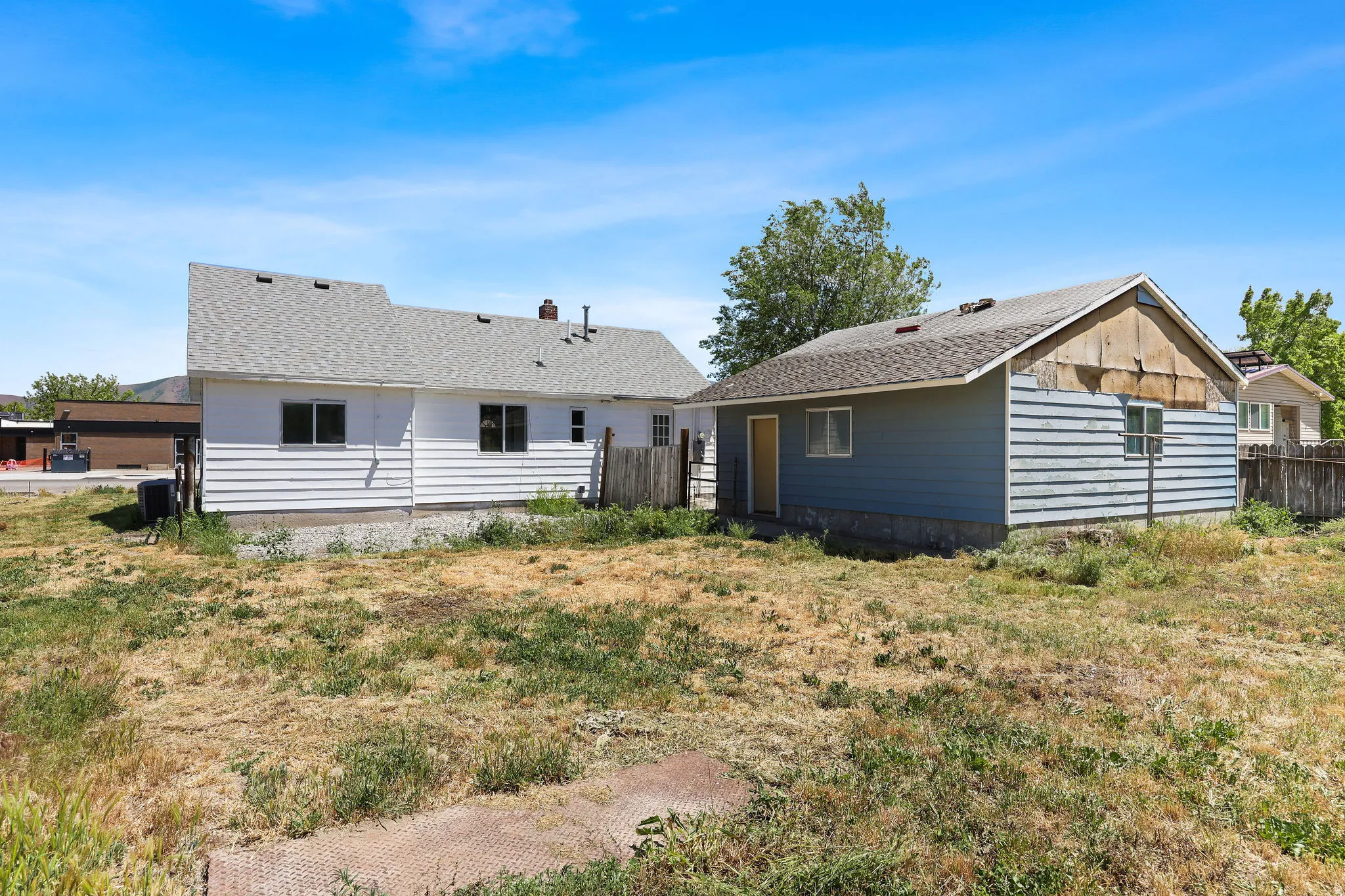 Expansive lot featuring a primary residence with white siding and a separate blue-sided auxiliary structure