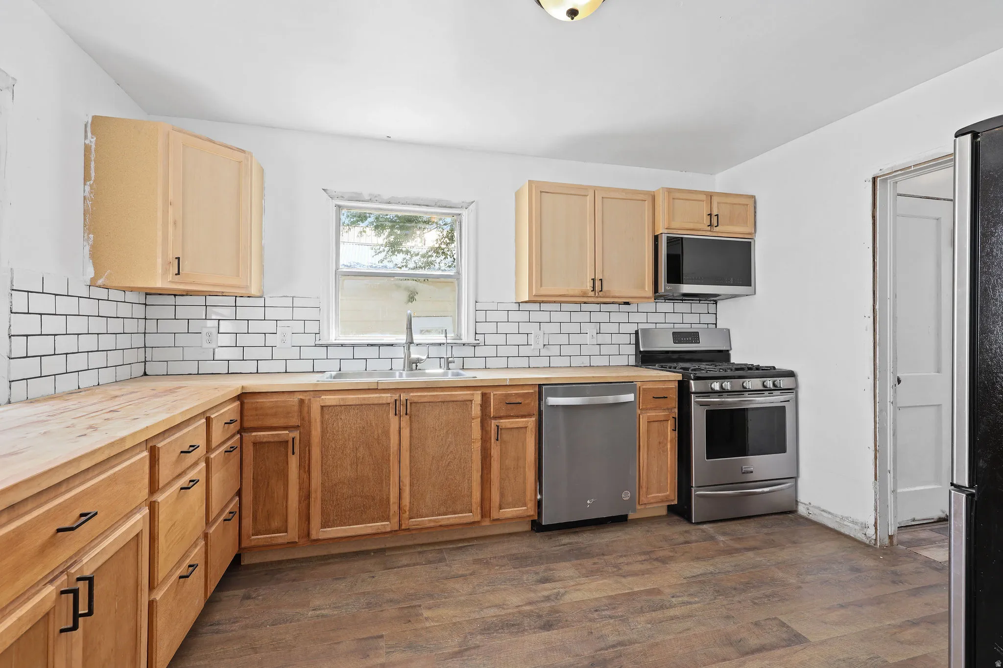 Kitchen featuring wood-finish flooring, natural wood cabinetry, wood countertops, and white subway tile backsplash