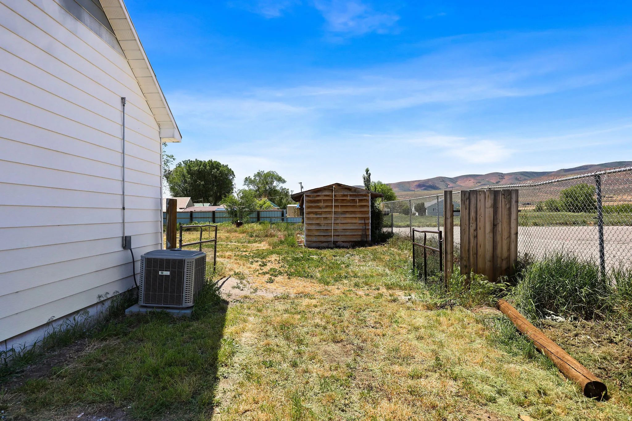 Expansive outdoor space featuring a detached storage shed and chain-link fencing
