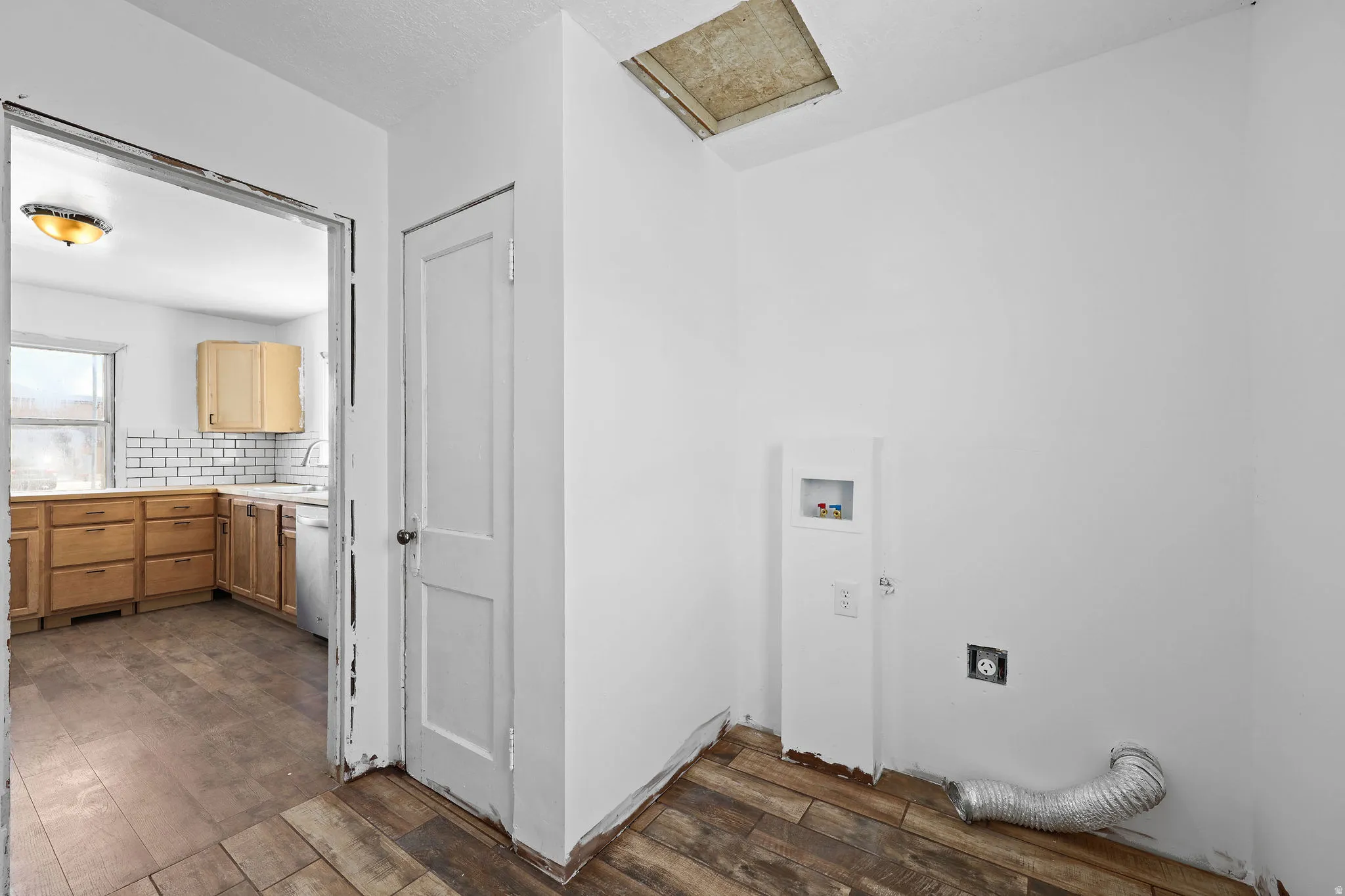 Utility area featuring wood-finish flooring, white walls, and a laundry hookup