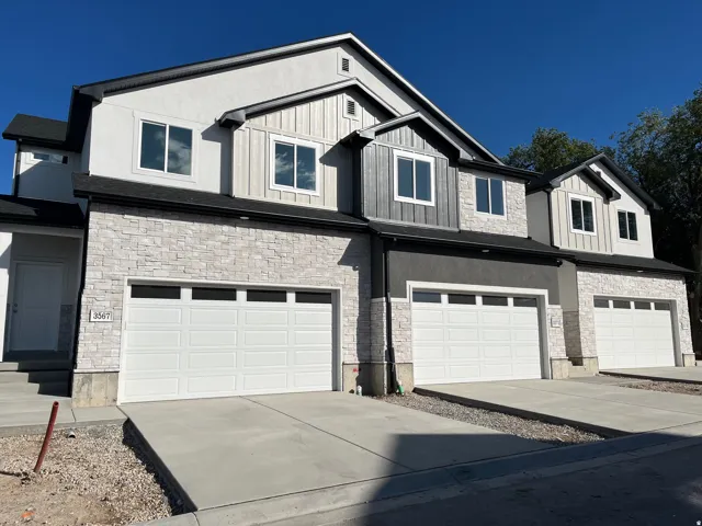 Modern townhome exterior featuring light-colored stacked stone and vertical siding accents