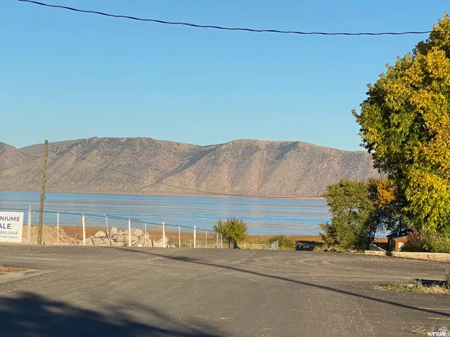 Paved road frontage with a water body and mountainous backdrop