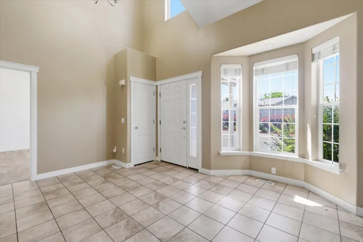 Foyer featuring a high vaulted ceiling, large bay windows, neutral-toned tile flooring, and a double entry door
