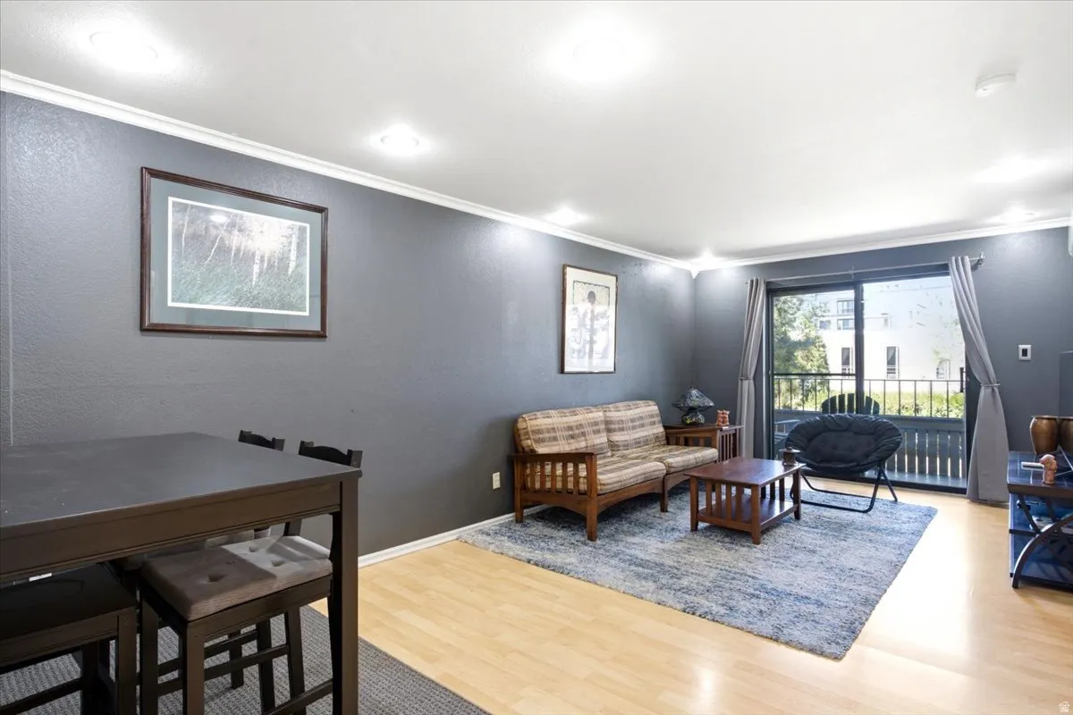 Open-concept living area featuring light wood-finish flooring, recessed lighting, and crown molding