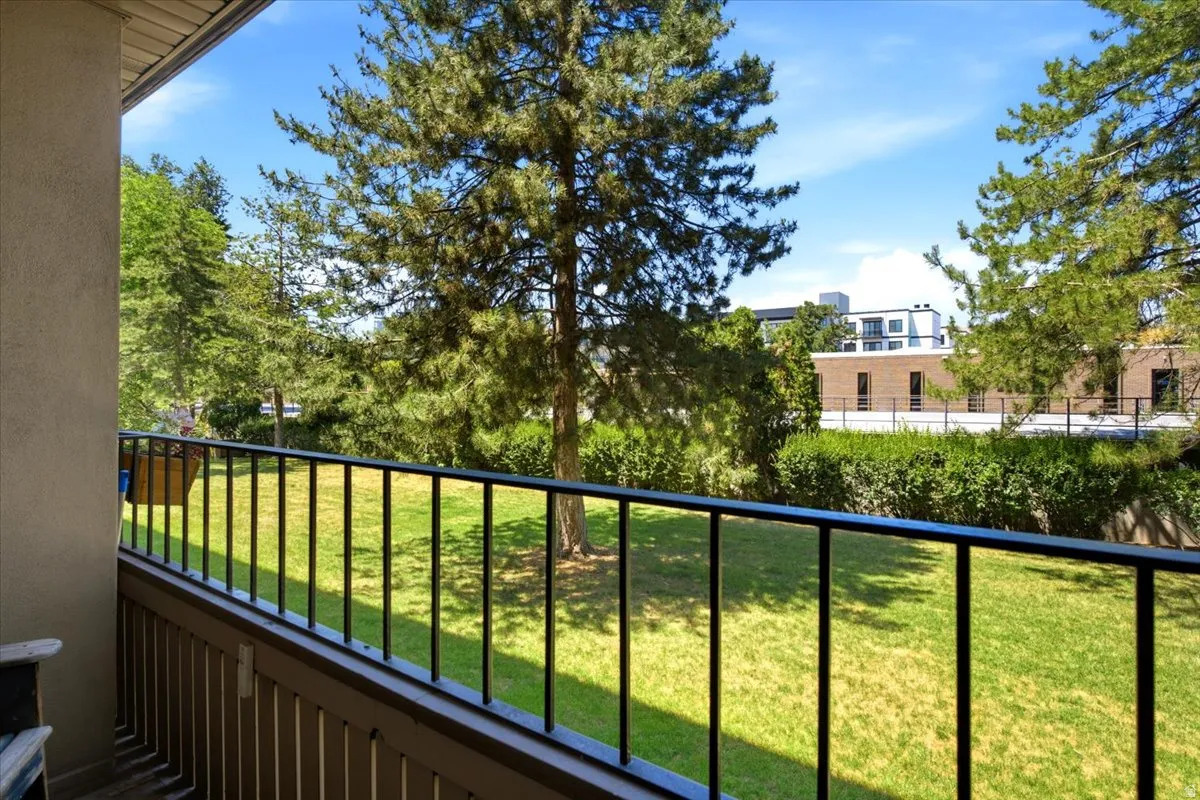 Private balcony featuring an open-rail design and verdant green landscaping