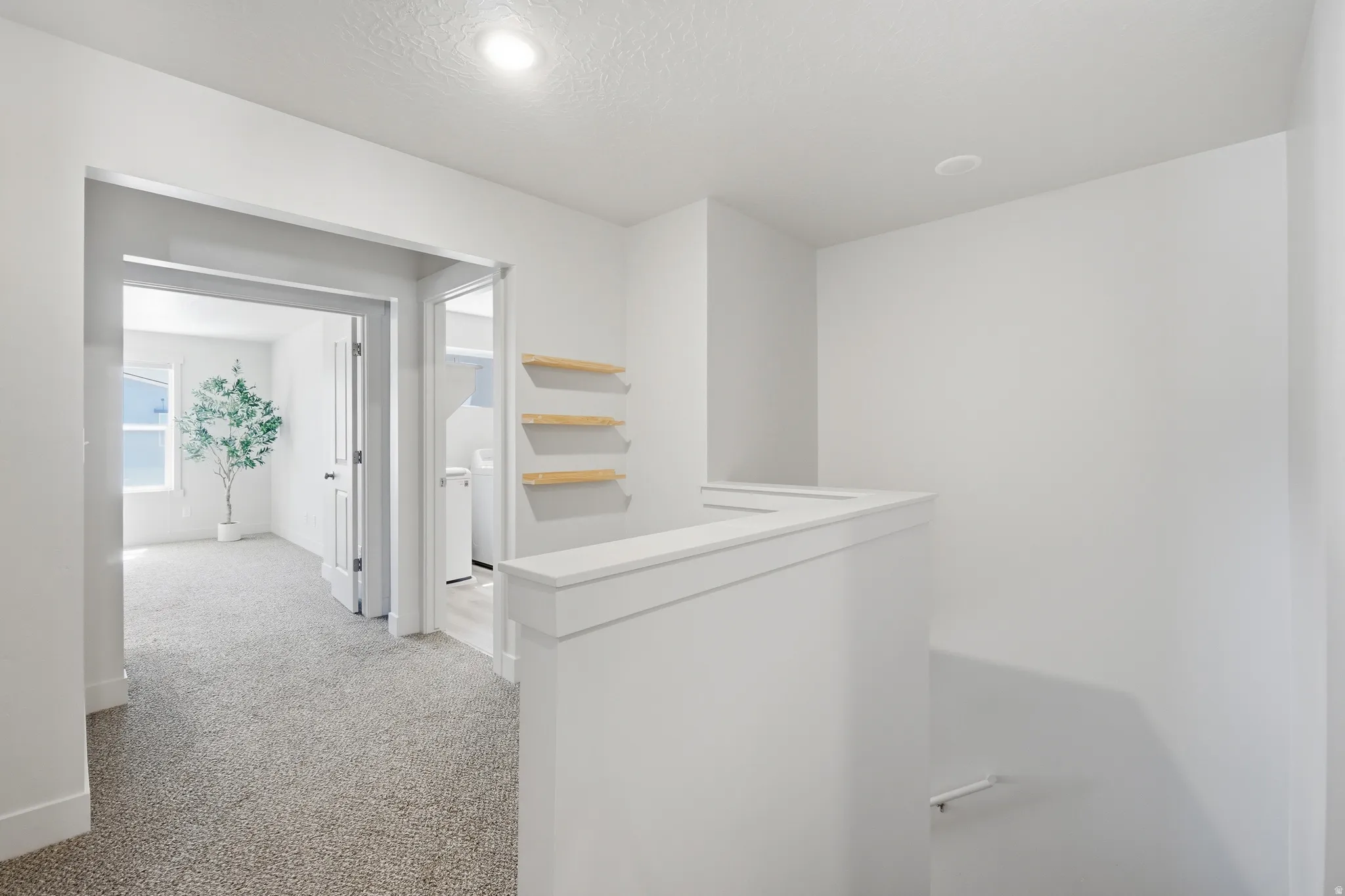 Upper landing with light gray carpeting, white walls, recessed lighting, and a white balustrade