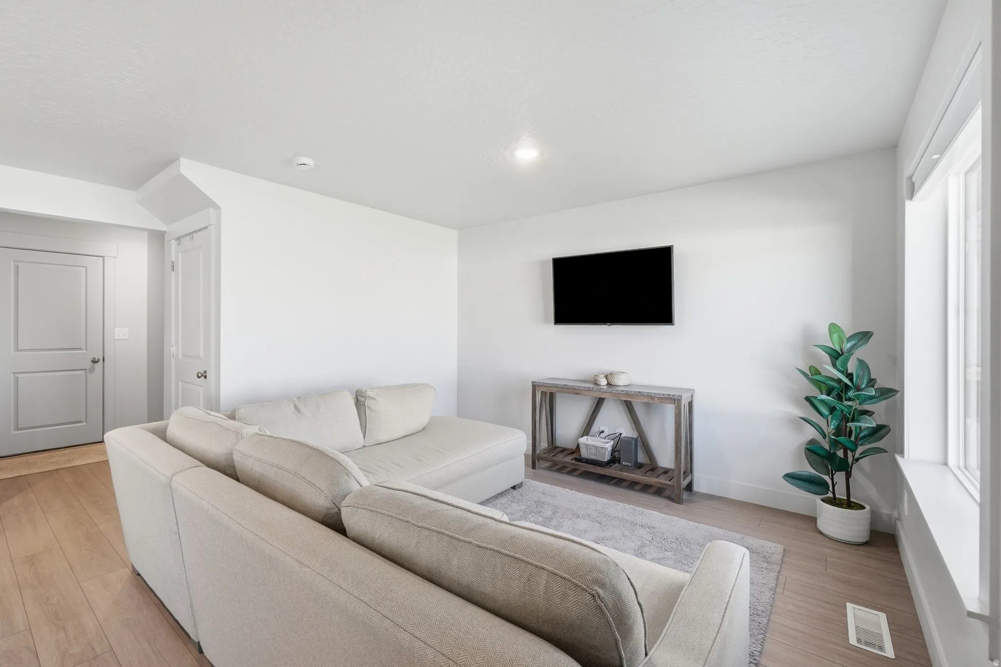 Living area featuring wood-finish flooring, white walls, and a recessed ceiling light
