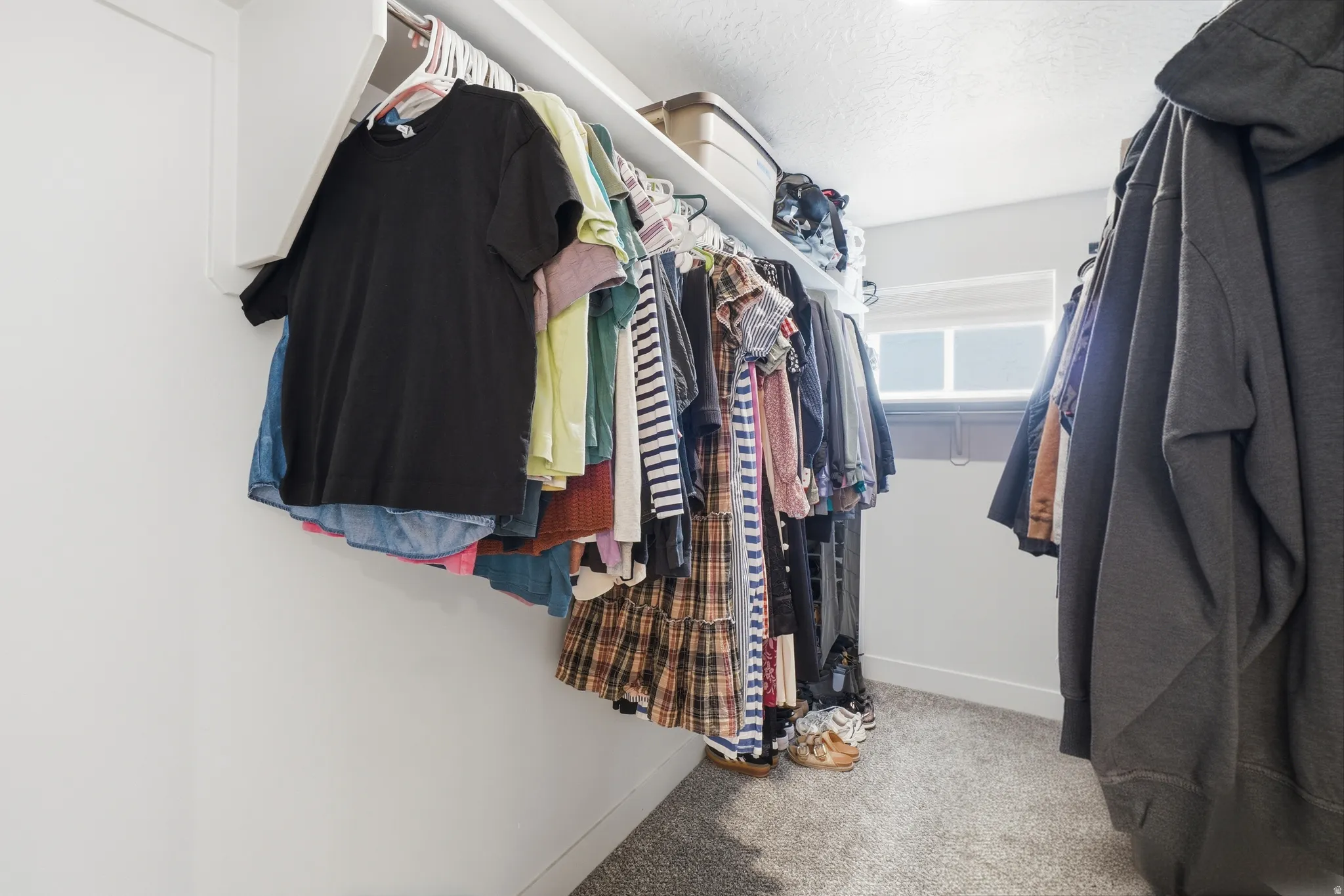 Walk-in closet featuring built-in shelving, hanging rods, and a window with blinds