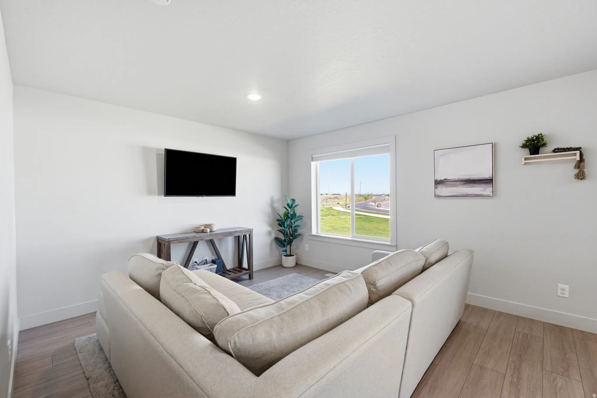 Bright living space featuring a large window, a wall-mounted television, recessed lighting, and wood-finish flooring