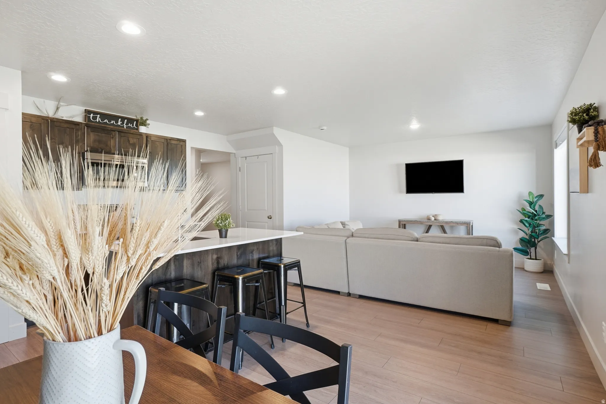 Open-concept living area featuring wood-finish flooring throughout, recessed lighting, and bright white walls