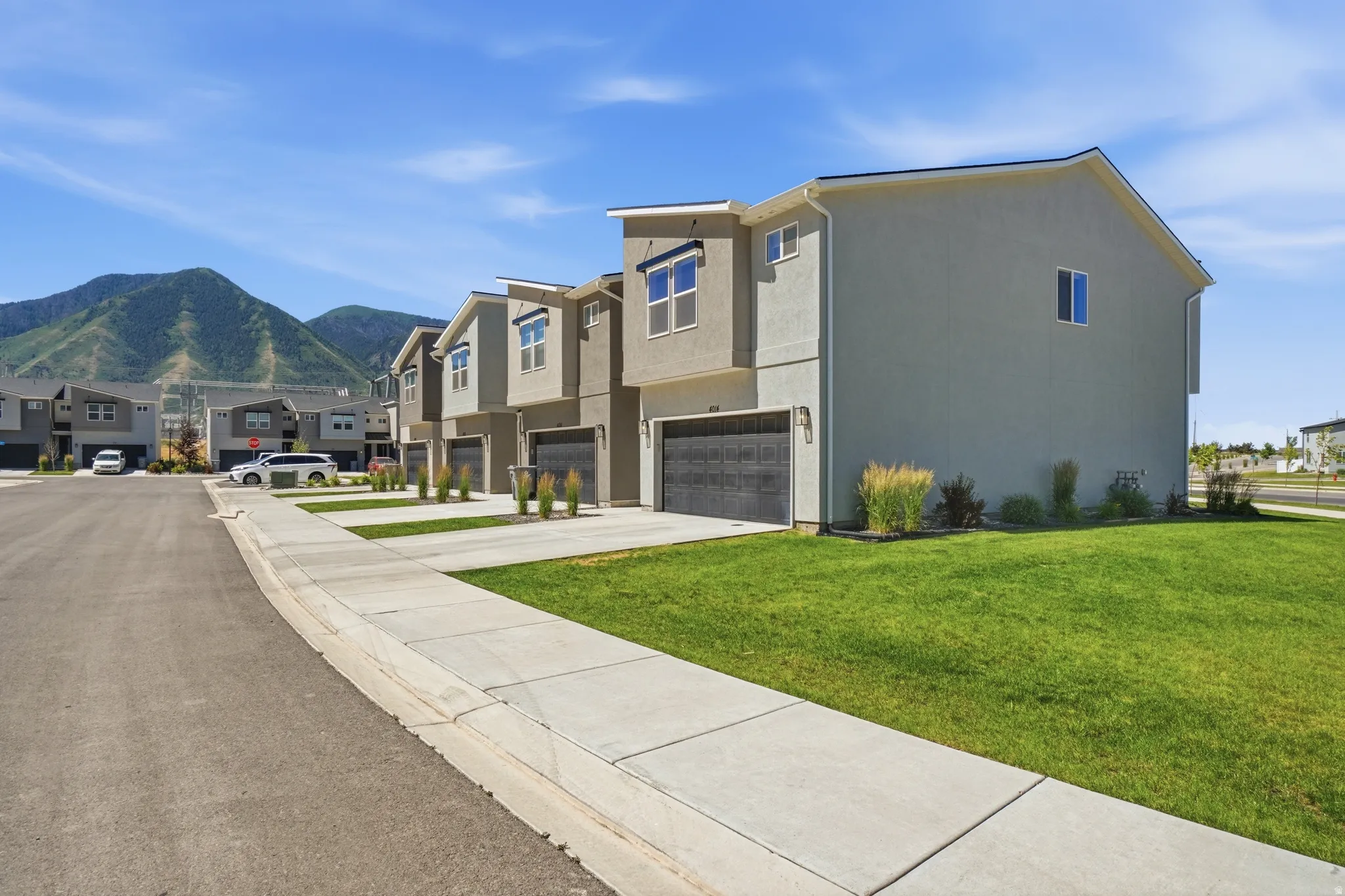 Modern townhome exterior featuring stucco siding and dark garage doors