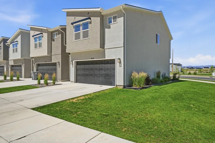 Contemporary exterior featuring stucco siding, multiple windows with dark trim, and a two-car garage