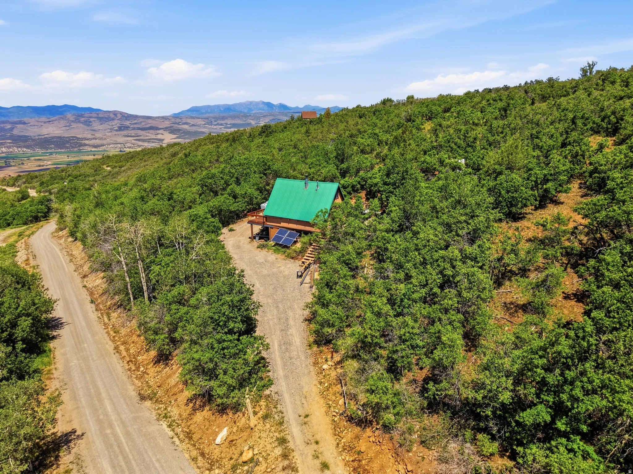 Hillside property featuring a cabin-style residence with a green metal roof and a wood-finish exterior