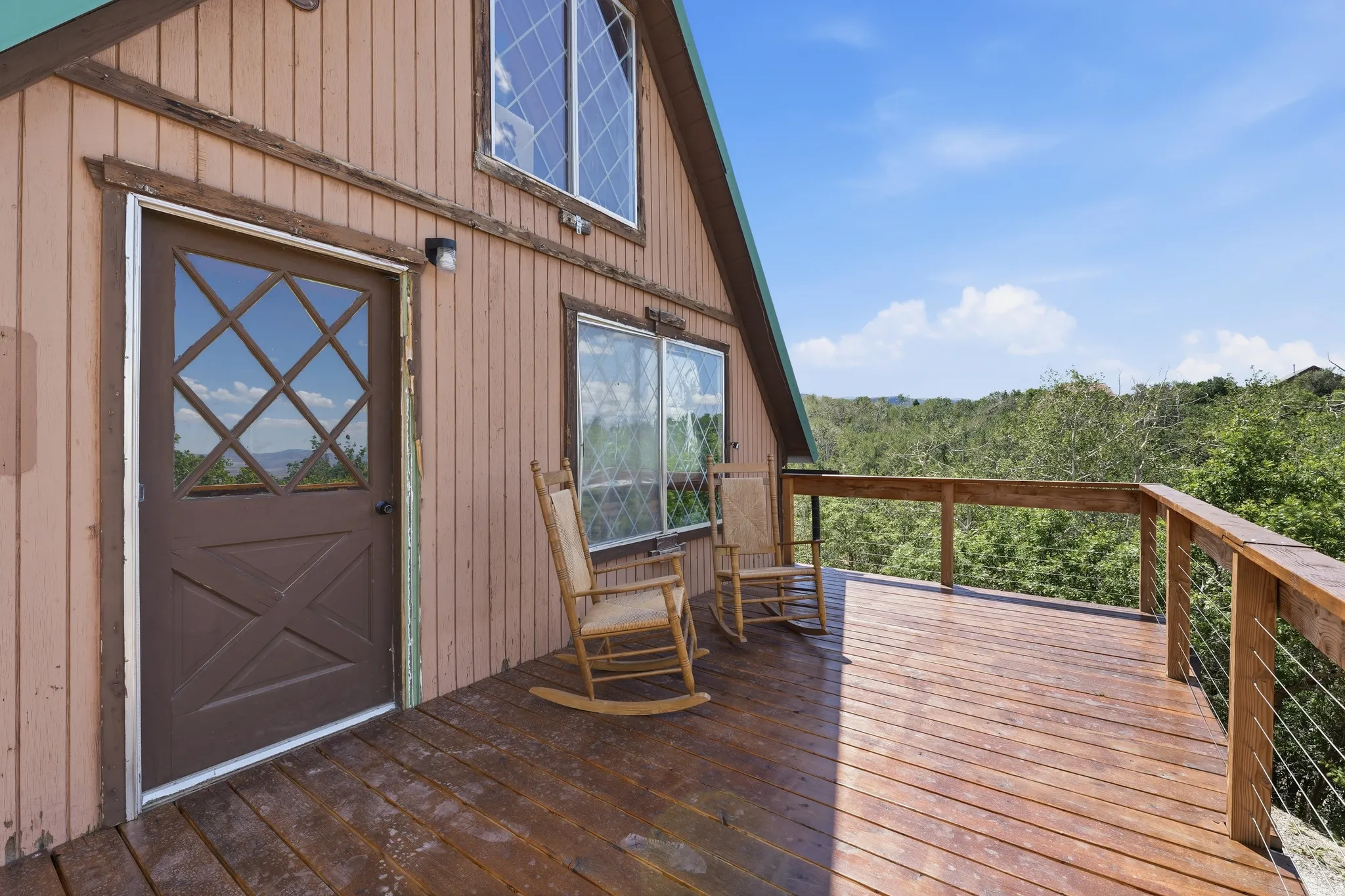 Expansive wood deck with cable railing overlooking a wooded landscape