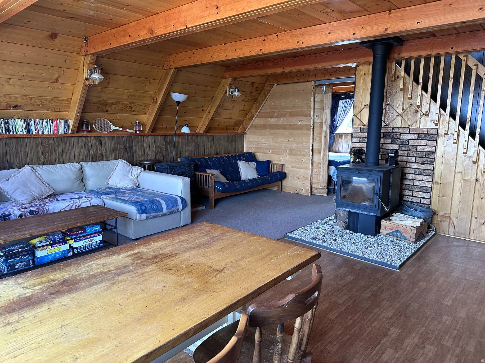 Open-concept living space featuring wood-finish flooring and a freestanding wood-burning stove with a brick and gravel hearth