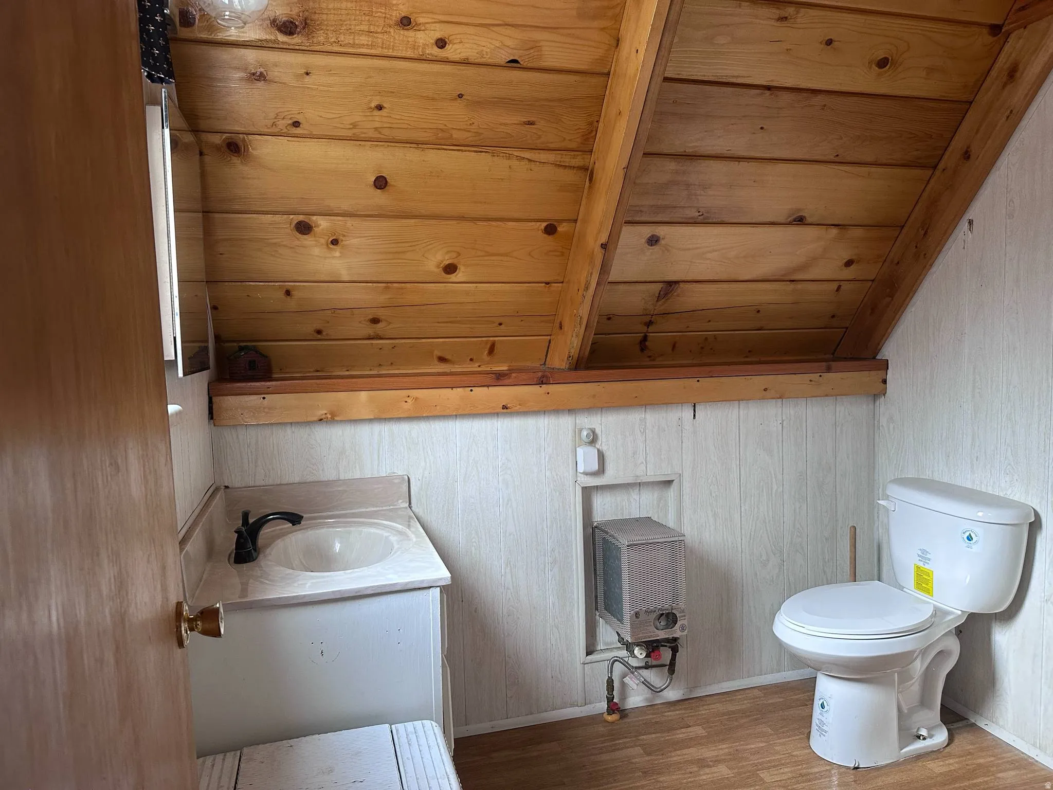 Bathroom with wood-finish flooring, white paneling, and a natural wood planked ceiling