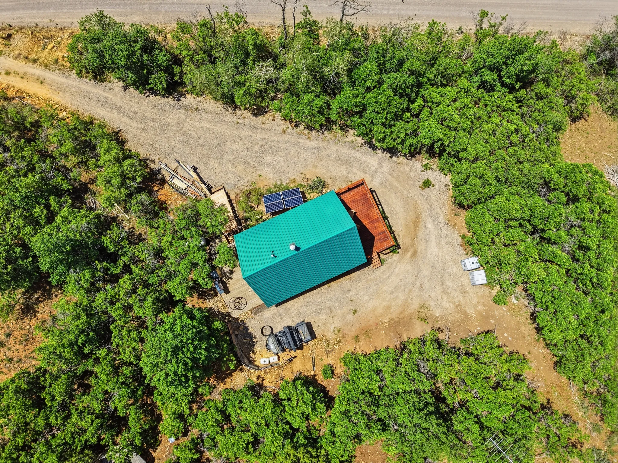 Compact structure with a vibrant green metal roof, surrounded by extensive natural foliage