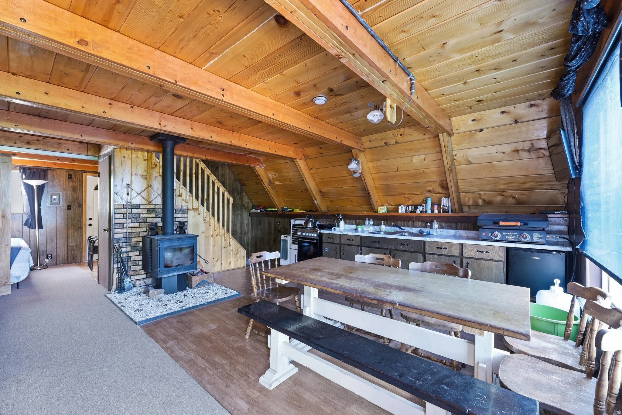 Open-concept living area with extensive wood-paneling and exposed ceiling beams