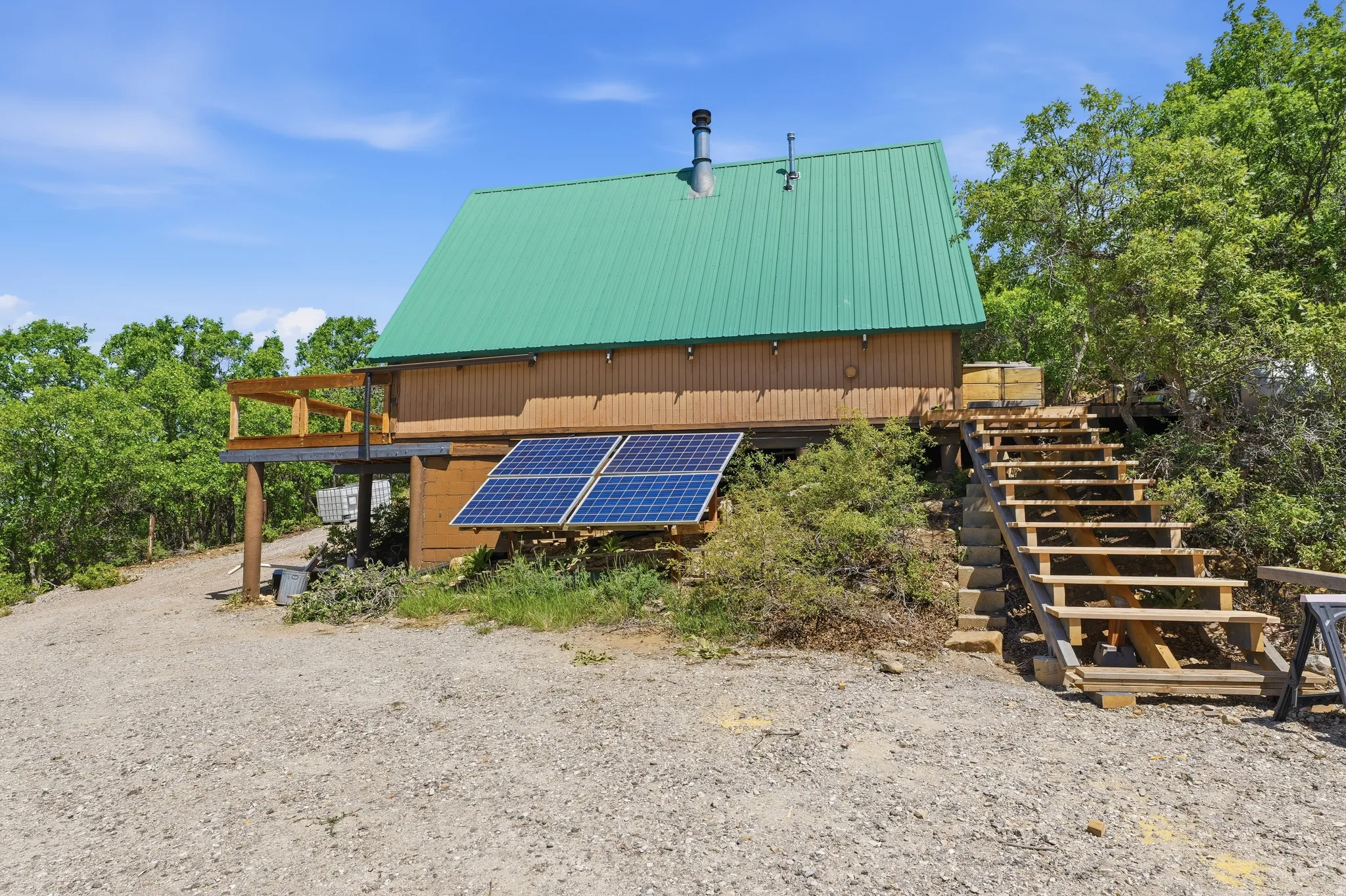 Wood-sided structure featuring a green metal roof and an outdoor deck