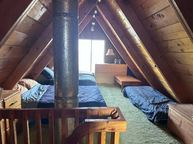 Vaulted ceiling with exposed wood beams, finished wood plank walls, and a prominent metal flue