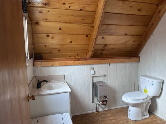 Bathroom with wood-finish flooring, white paneling, and a natural wood planked ceiling